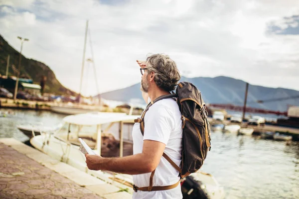 Uśmiechnięty turysta dojrzały mężczyzna stojący z mapą i plecakiem w pobliżu t — Zdjęcie stockowe