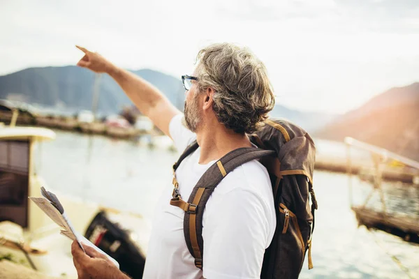 Glimlachende toerist volwassen man staan met kaart en rugzak in de buurt t — Stockfoto