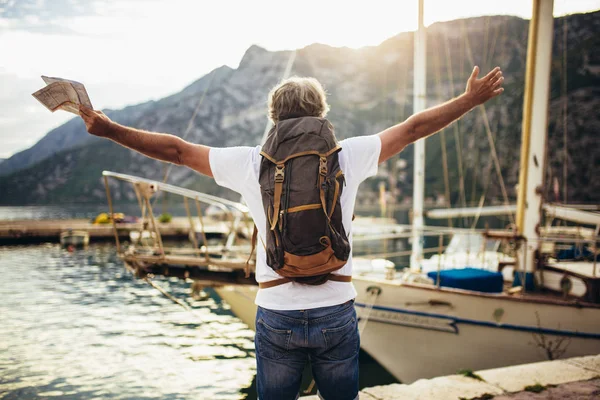 Gülümseyen turist olgun bir adam haritası ve sırt çantası yanında duruyor. — Stok fotoğraf