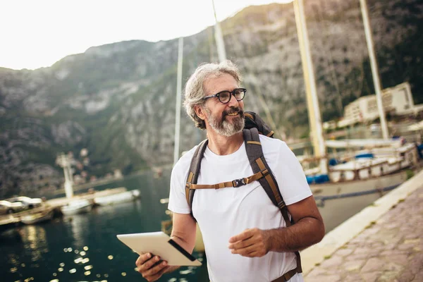 Mosolygós turista érett férfi áll digitális tabletta és vissza — Stock Fotó