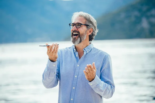 Reifer Mann spricht auf dem Smartphone im Yachthafen. — Stockfoto