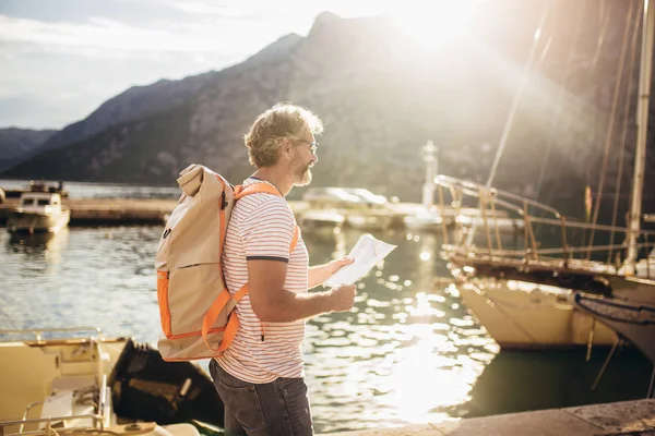 Sorridente turista maturo uomo in piedi con mappa e zaino vicino t — Foto Stock