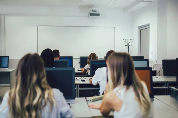 Estudiantes universitarios sentados en un aula, usando computadoras durante — Foto de Stock