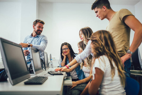 Студенты колледжа сидят в классе, используя компьютеры во время
 