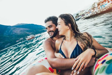 Şişme yüzük ve erkek arkadaşı üzerinde yüzen bikinili mutlu kadın.