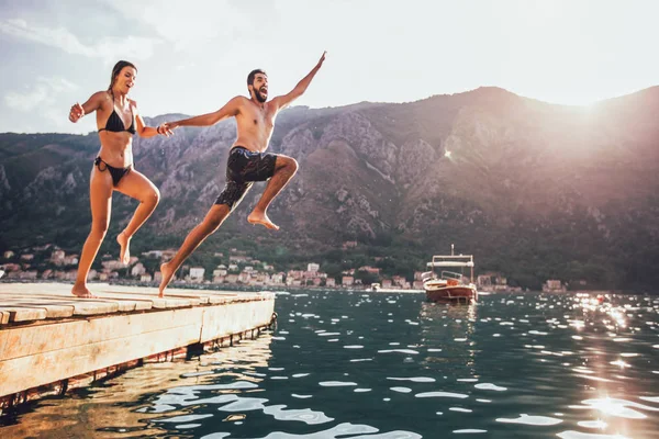 Jong stel springt van een pier in het water. Gedeocaliseerd — Stockfoto