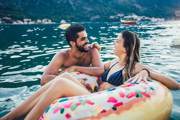 Glückliche Frau im Bikini schwimmt auf aufblasbarem Ring und ihrem Freund — Stockfoto