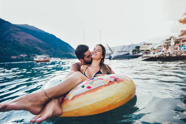Mujer feliz en bikini flotando en el anillo inflable y su boyfri — Foto de Stock