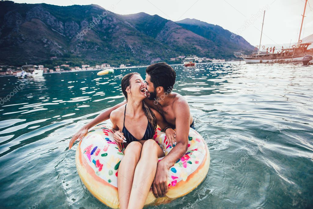 Happy woman in bikini floating on inflatable ring and her boyfri