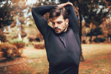 Genç sporcu parkta esniyor, egzersiz yapıyor.. 