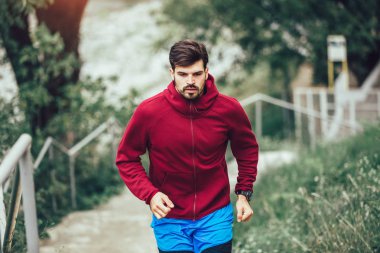 Genç adam sabah parkta koşuyor.