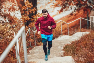 Genç adam sabah parkta koşuyor.