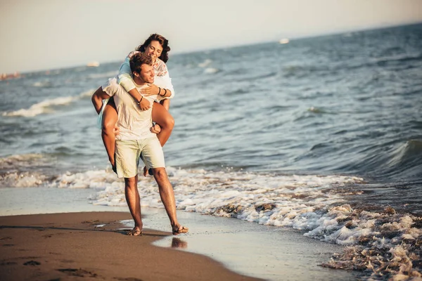 Pohledný mladý muž, který se na pláži svezne na holku. — Stock fotografie