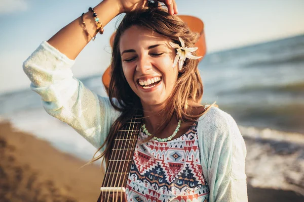 Smiling girl walking on the beach holding a guitar in her hands. — Stock Photo, Image