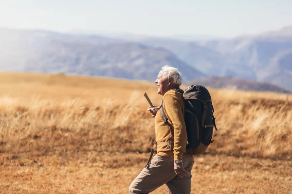 Uomo anziano in escursione attraverso la bella campagna in autunno. — Foto Stock