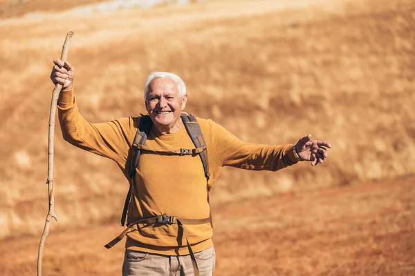 Senior man op wandeling door prachtig landschap in de herfst. — Stockfoto