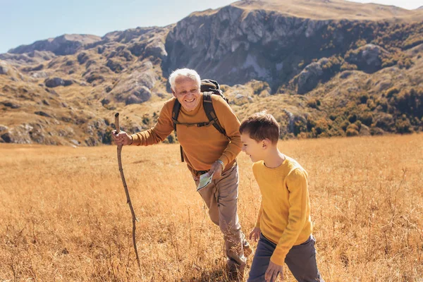 Старший мужчина с внуком на прогулке по стране осенью. — стоковое фото