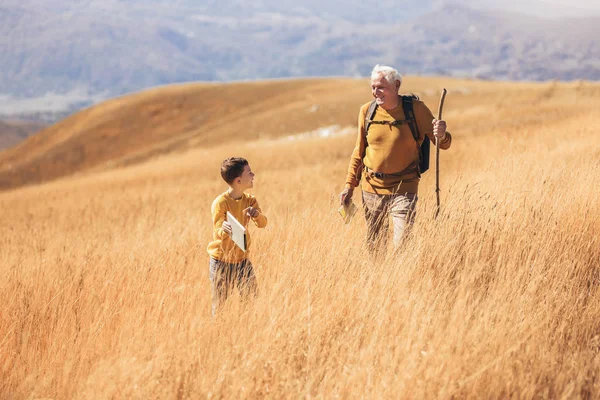 Homem sênior com neto em passeio rural no outono. — Fotografia de Stock