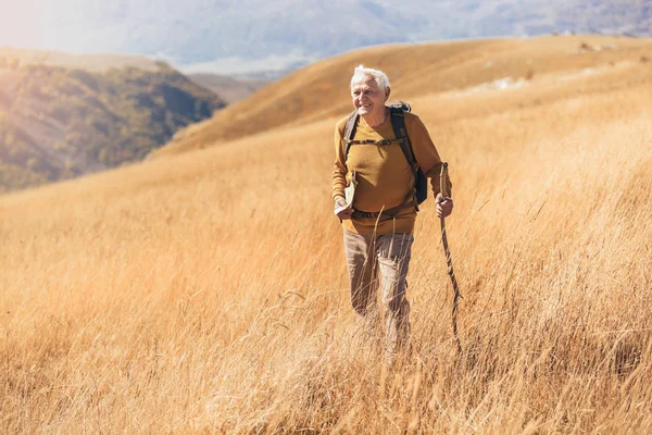 Senior man op wandeling door prachtig landschap in de herfst. — Stockfoto