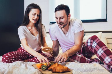 Romantik mutlu çift yatakta kahvaltı yapıyor.