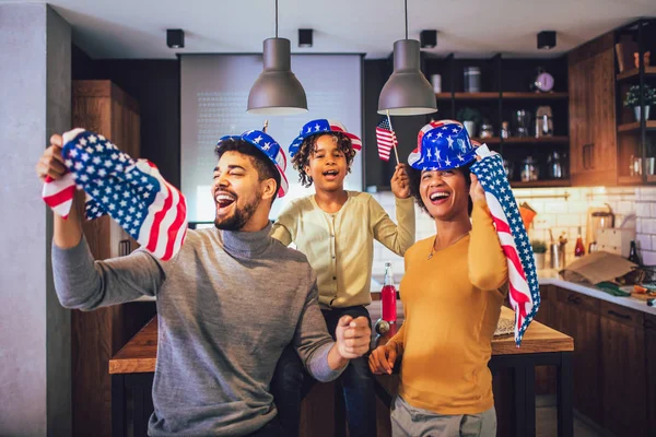 Семья в гостиной 4 июля с улыбающимися флагами — стоковое фото