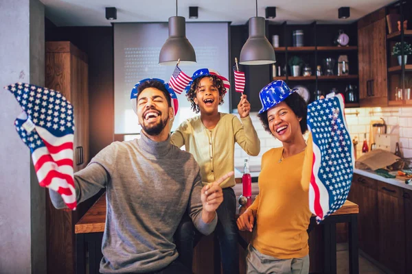 Aile, 4 Temmuz 'da oturma odasında bayraklarla gülümsüyor. — Stok fotoğraf