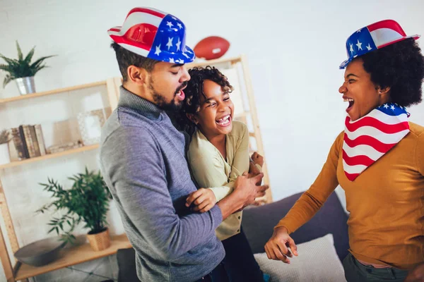 Familie im Wohnzimmer am 4. Juli mit lächelnden Fahnen — Stockfoto