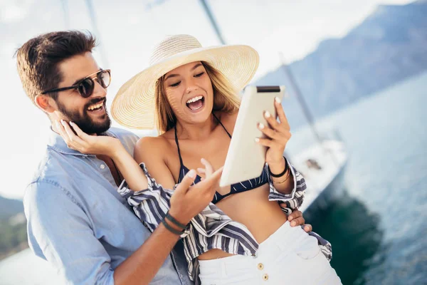 観光の海のリゾートのデジタルタブレットを使用して港のそばを歩く幸せな若いカップル — ストック写真