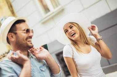 Alışveriş sonra sokakta yürürken onların omuzlarında alışveriş torbaları tutmak yakışıklı genç çift aşağı