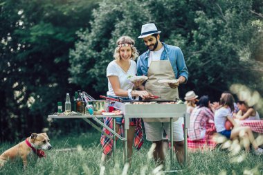 Arkadaşlar barbekü yapıyor ve öğle yemeği yiyor.