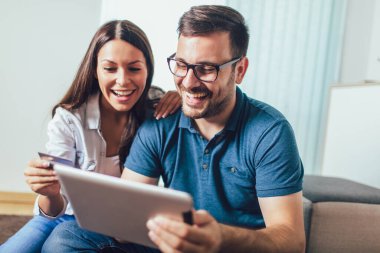 Tablet pc bilgisayar ve kredi veya banka kartı alışveriş online evde ile Gülümseyen mutlu çift