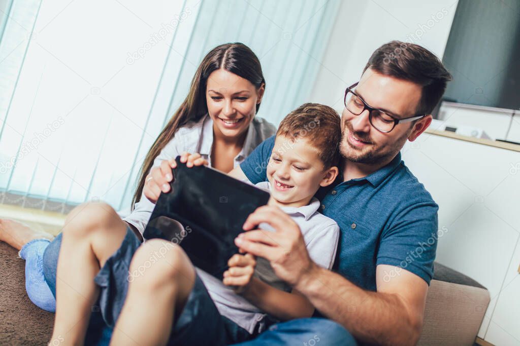 Happy family enjoying together at home, using tablet and having great time together.