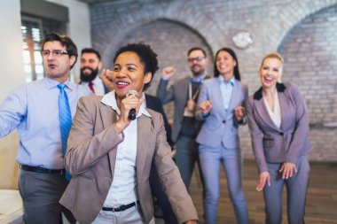 Kapalı alanda ilginç bir takım çalışması. Takım oluşturma semineri sırasında takım çalışması yapan iş adamları karaoke söylüyor..