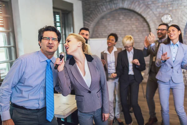 Funny teambuilding indoors activity. Business people making team training exercise during team building seminar singing karaoke.