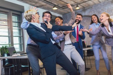 Kapalı alanda ilginç bir takım çalışması. Takım oluşturma semineri sırasında takım çalışması yapan iş adamları karaoke söylüyor..
