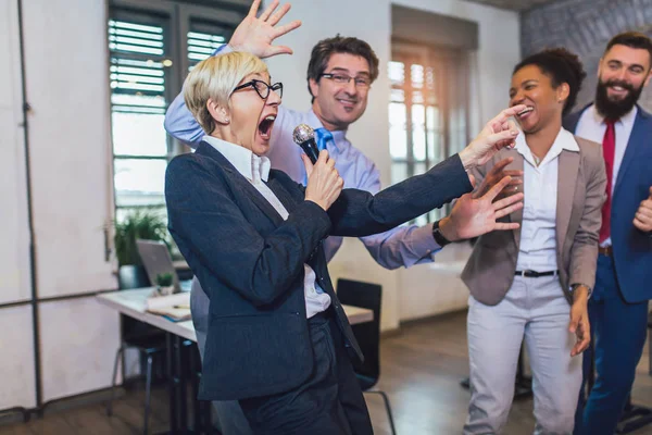 Funny teambuilding indoors activity. Business people making team training exercise during team building seminar singing karaoke.