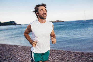 Koşan adam sahilde koşuyor. Erkek atlet antrenmanı dışarıda.. 