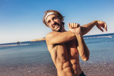 Sahilde koşmak önce germe yapan genç yakışıklı spor erkek