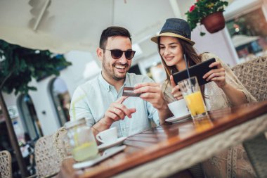 Bir kafede otururken online mutlu genç çift alışveriş. 