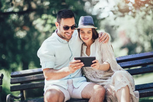 Happy couple watching media in a digital tablet outdoor