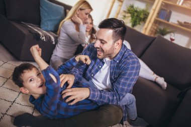Evde oynayan çocukları olan mutlu bir aile. Aile yerde oturuyor ve birlikte oynuyor..