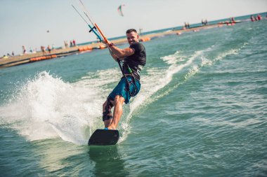 Profesyonel bir mutant nehirde zor bir numara yapar. Uçurtma sörfü yapan sörf fotoğrafçısı dalgaların arasında hızla gider.