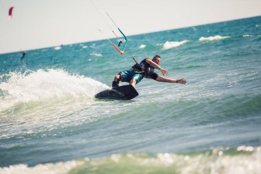 Profesyonel kiter zor hüner güzel bir arka plan üzerinde yapar. Kitesurfing Kiteboarding eylem fotoğraflar adam dalgalar arasında hızlı bir şekilde gider