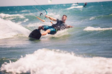 Profesyonel kiter zor hüner güzel bir arka plan üzerinde yapar. Kitesurfing Kiteboarding eylem fotoğraflar adam dalgalar arasında hızlı bir şekilde gider