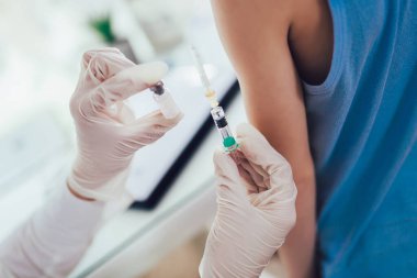 Pediyatrist küçük çocuğa aşı yapar. Kadın doktor küçük çocuğu aşılıyor..