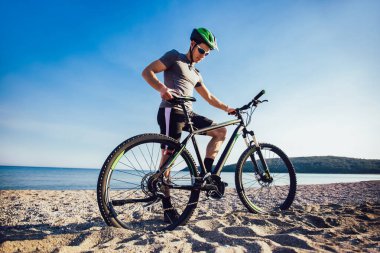 Adam sahilde dağ bisikleti sürmek. Spor ve aktif yaşam konsepti.
