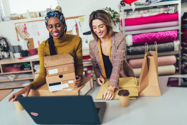 Satış çevrimiçi. Dükkanlarında çalışan kadınlar. İnternetten yeni siparişleri kabul ediyorlar ve müşteriler için mal paketliyorlar..