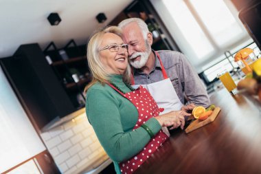 Mutfakta yemek hazırlayan yaşlı çift. Mutfakta sarılan mutlu yaşlı çift.