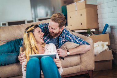 Birbirini seven bir çift kanepede oturur ve dijital tablet kullanır, eğlenir.. 