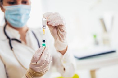 Doktor aşı ve şırınga tutuyor. Önleme ve aşılama için kullanılır..
